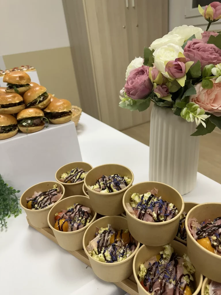 Zoom sur le buffet réalisé par Maison Mélia avec mini burgers et des garnitures présenté sur table lors d’un événement.