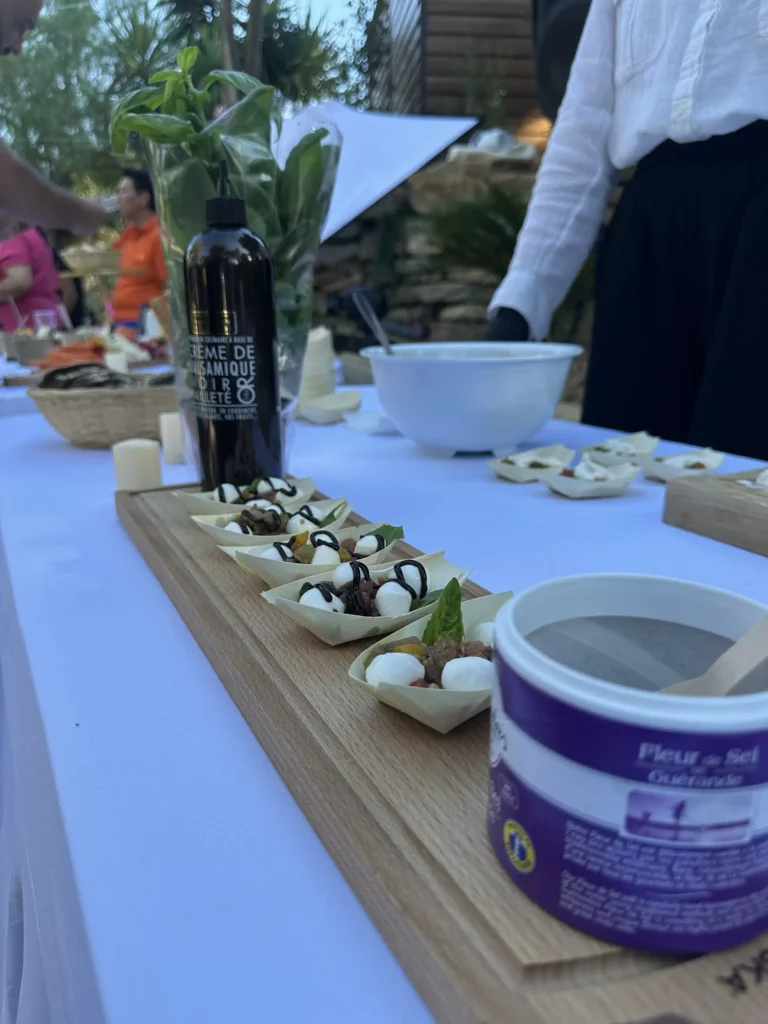 Présentation de bouchées apéritives sur un plateau en bois avec mozzarella, basilic et crème balsamique lors d’un événement.