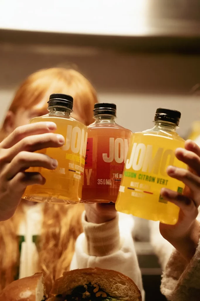 Personnes avec des bouteilles de thé glacé JOMO au-dessus d'un burger.