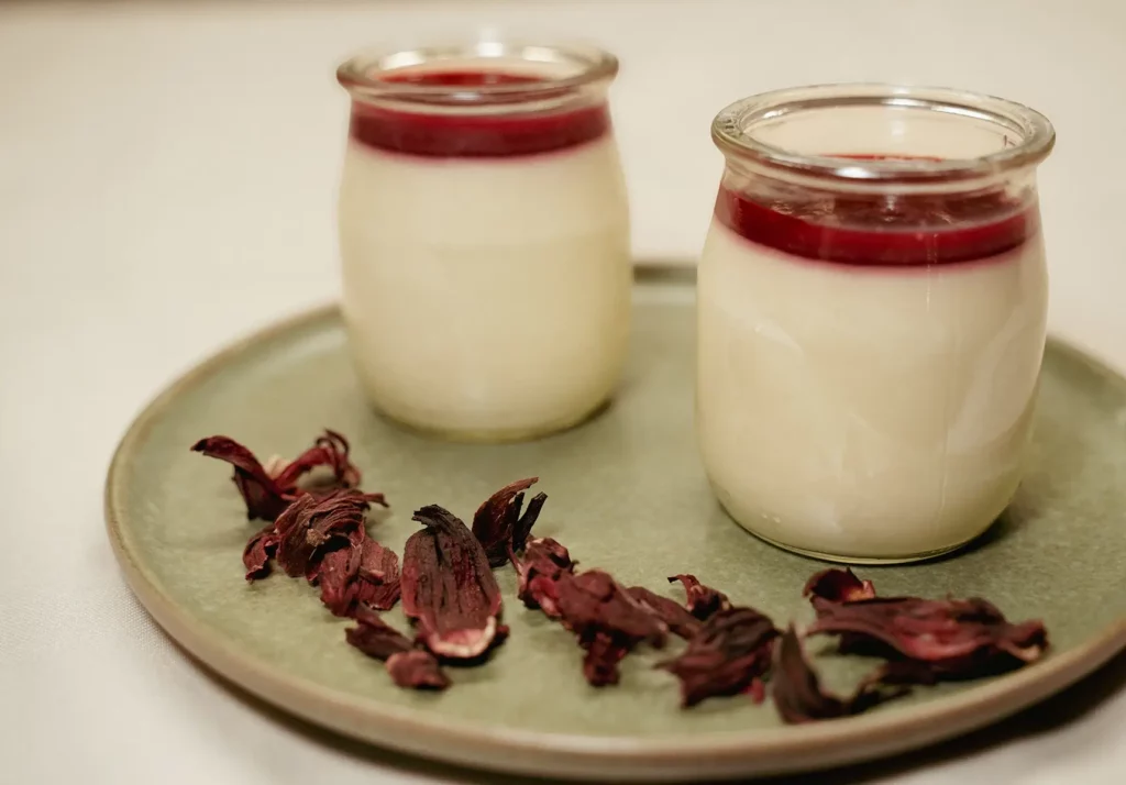 Desserts en verrines type panna cotta avec coulis de fruits rouges, présentés sur assiette.